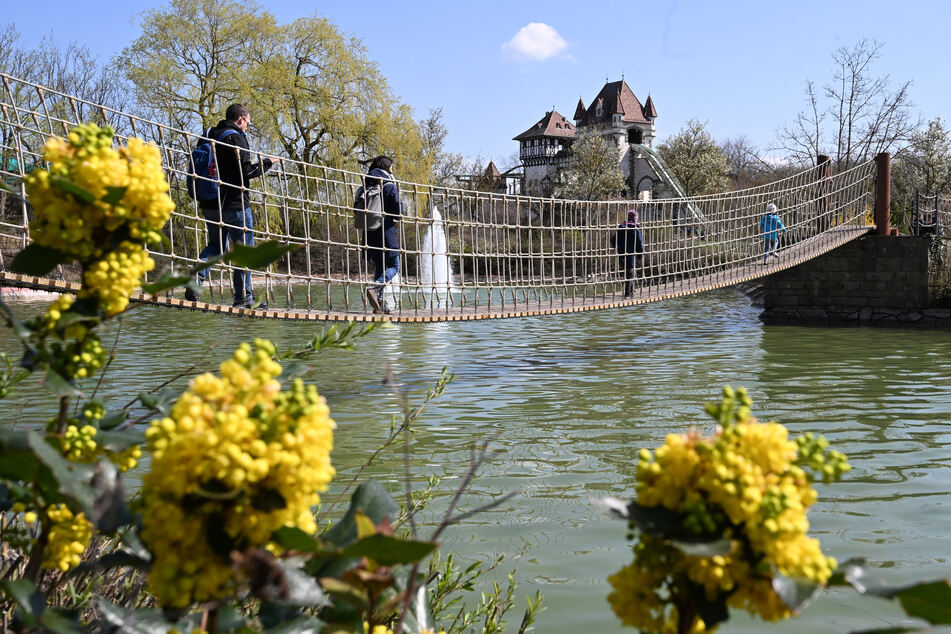 Im Freizeitpark Tripsdrill bei Cleebronn laufen Besucher auf einer Hängebrücke über ein Wasserbecken.