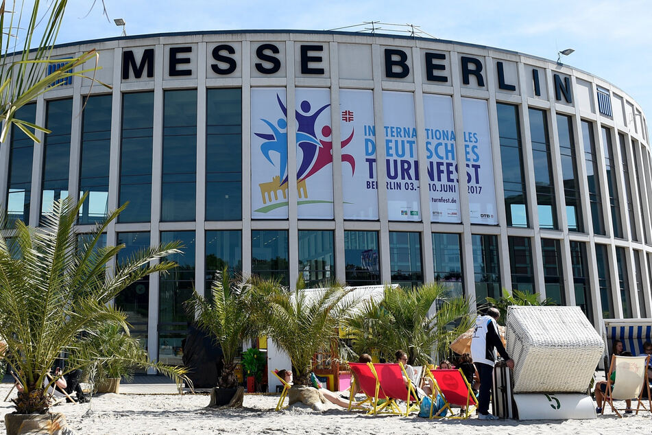 Besucher des Deutschen Turnfestes sitzen am letzen Tag der Veranstaltung, auf einer Strandlandschaft vor den Gebäuden des Messe in Berlin.