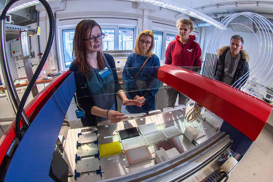 Im Biotechnologie-Labor der HS Mittweida erklärt Dominique Tuch (30, l.) Jessica Kurucz (18), ihrem Vater Jörg Poetzsch (49) und Sören Tara (18) einen Roboter.