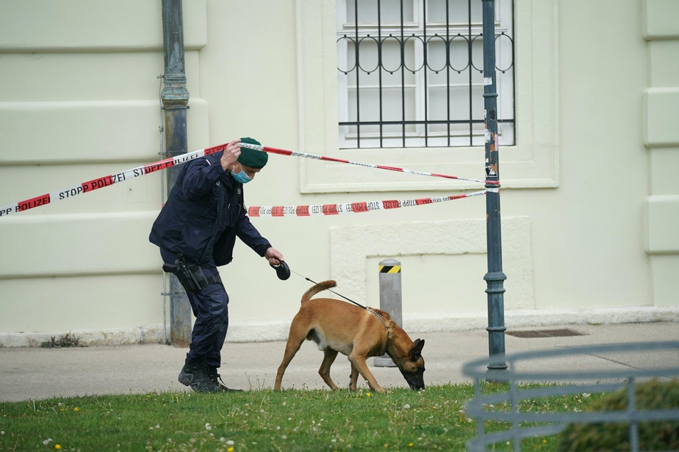 Ein Polizist ist vor der Wiener Hofburg mit einem Spürhund auf der Suche nach einer Bombe.