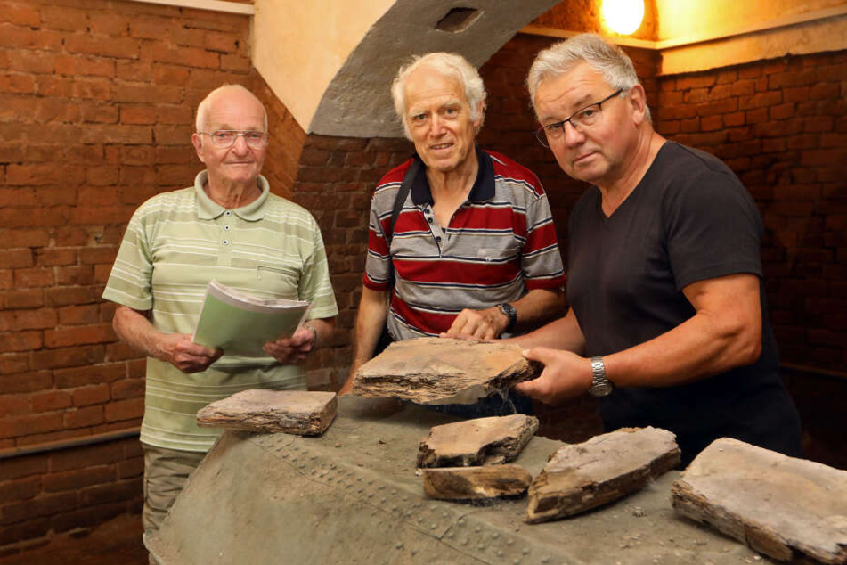 Manfred Geyer (81), Alfred Lehmann und Christian Bretschneider mit den Überresten eines Holzsargs ein, die sich ebenfalls im Grufthaus befinden.
