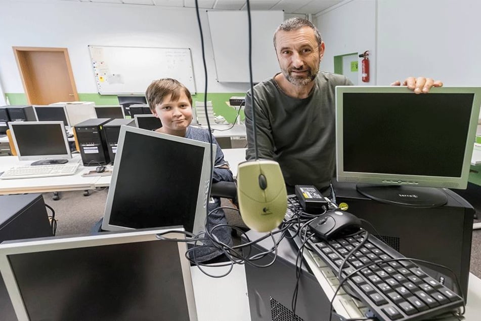 Informatiklehrer Thomas Georgie (54) und sein Schüler Ian Menge (12) zeigen kaputte Monitore, Computer und Tastaturen an der Oberschule Am Flughafen.
