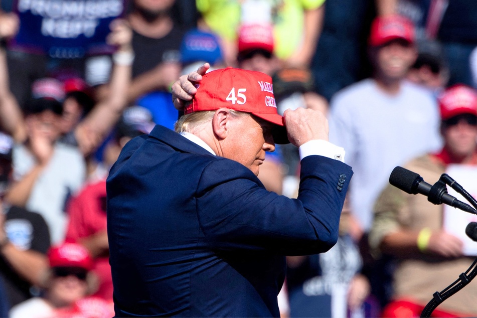 Donald Trump putting on a MAGA hat during a Make America Great Again rally at Laughlin/Bullhead International Airport in Bullhead City, Arizona on October 28, 2020.