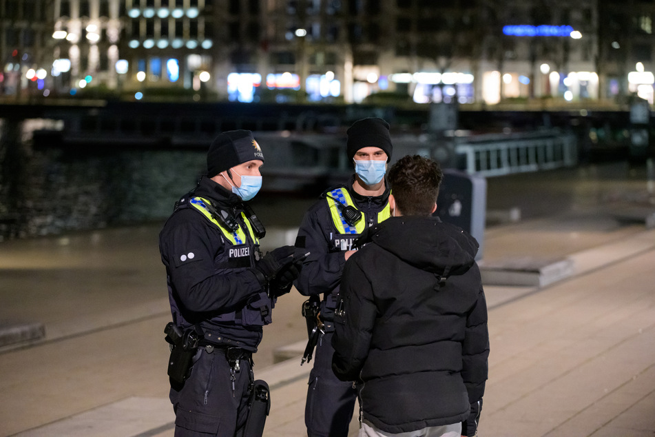 Polizisten kontrollieren am Jungfernstieg einen Mann, der sich nach 21 Uhr im Freien aufhält.