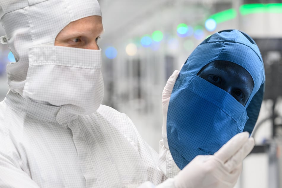 Lasertechnologie zum Spalten von Wafern: Ein Infineon-Mitarbeiter spiegelt sich in einem kreisrunden 300-Millimeter-Wafer zur Fertigung von Mikrochips.