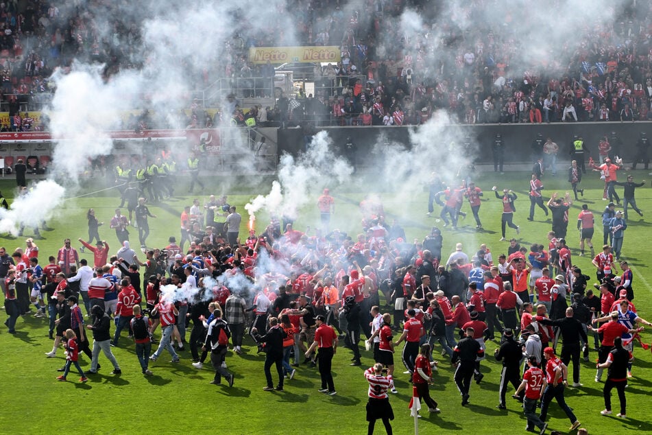 Nach dem geschafften Aufstieg stürmten Energie-Fans den Rasen, zündeten auch dort Pyro.