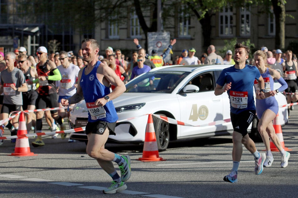 Wenige hundert Meter nach dem Start blockiert ein defektes Begleitfahrzeug die Marathon-Strecke und muss von den Teilnehmenden umlaufen werden.