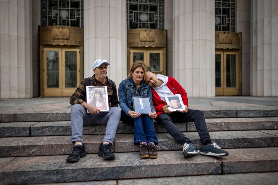 People hold photos of their children outside the Los Angeles Superior Court on February 11, 2026.
