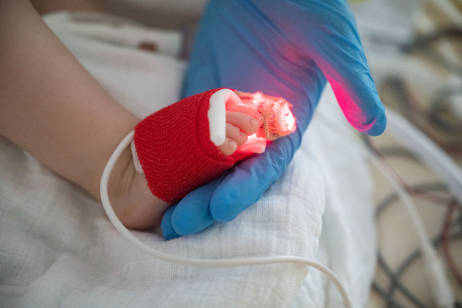 Eine Intensivpflegerin hält auf der Kinder-Intensivstation des Olgahospitals des Klinkums Stuttgart den Fuß eines am Respiratorischen Synzytial-Virus (RS-Virus oder RSV) erkrankten Patienten in der Hand.