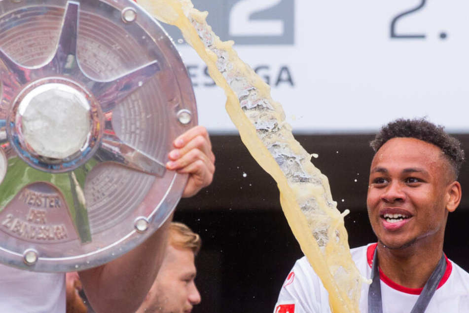 Nikolas Nartey überschüttet Salih Özcan mit Bier, der die Meisterschale der 2. Bundesliga in den Händen hält.
