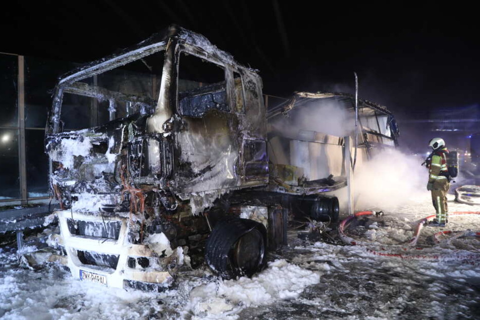 Feuerwehrleute löschen den völlig zerstörten Laster.