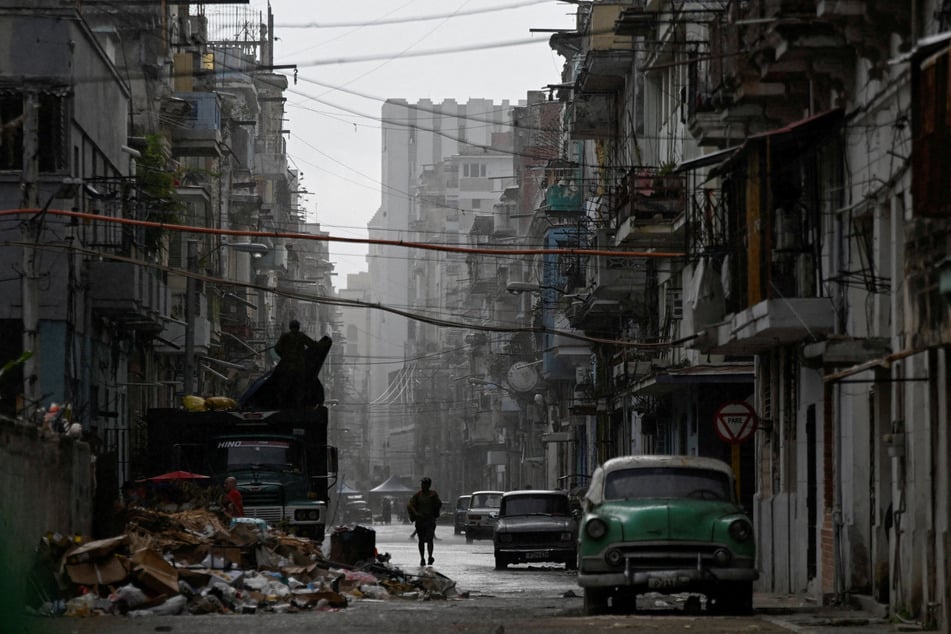 A man walks on a street in Havana in the rain as Cuba reconnected its electrical grid across much of the island on March 17, 2026.