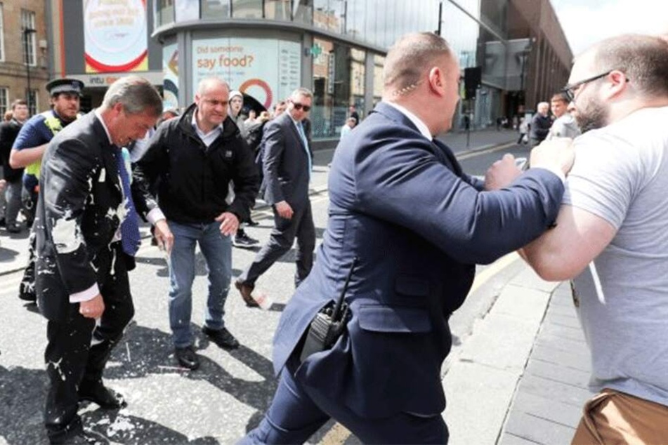Kurz nach der Attacke blickt Farage betreten zu Boden, während Bodyguards den Angreifer festsetzen.