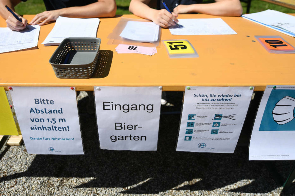 Zwei Mitarbeiter eines Biergartens notieren sich alle Gäste. Die Polizei greift bei Ermittlungen auf Gästedaten von Bewirtungsbetrieben zurück (Archivbild).