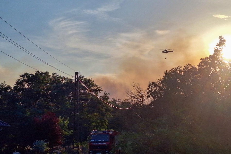 Mehrere Feuerwehren sind seitdem im Einsatz, auch ein Hubschrauber unterstützt die Löscharbeiten.