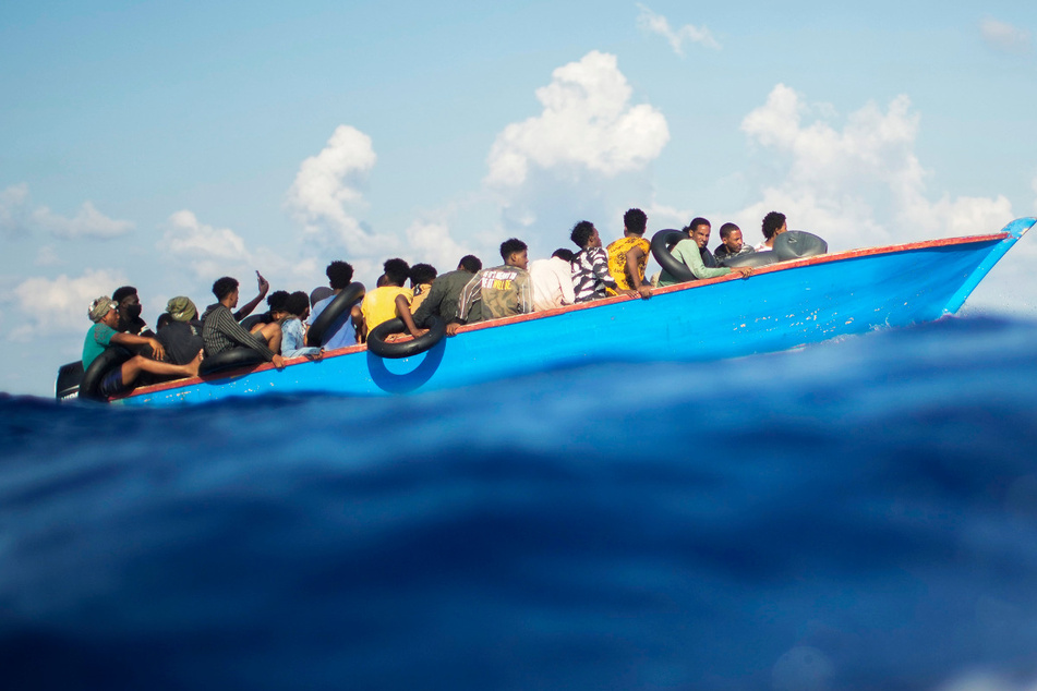 Migranten sitzen in einem Holzboot nahe der Insel Lampedusa - über das Mittelmeer erreichen immer wieder Flüchtlinge die Europäische Union, die Route gilt als sehr gefährlich.