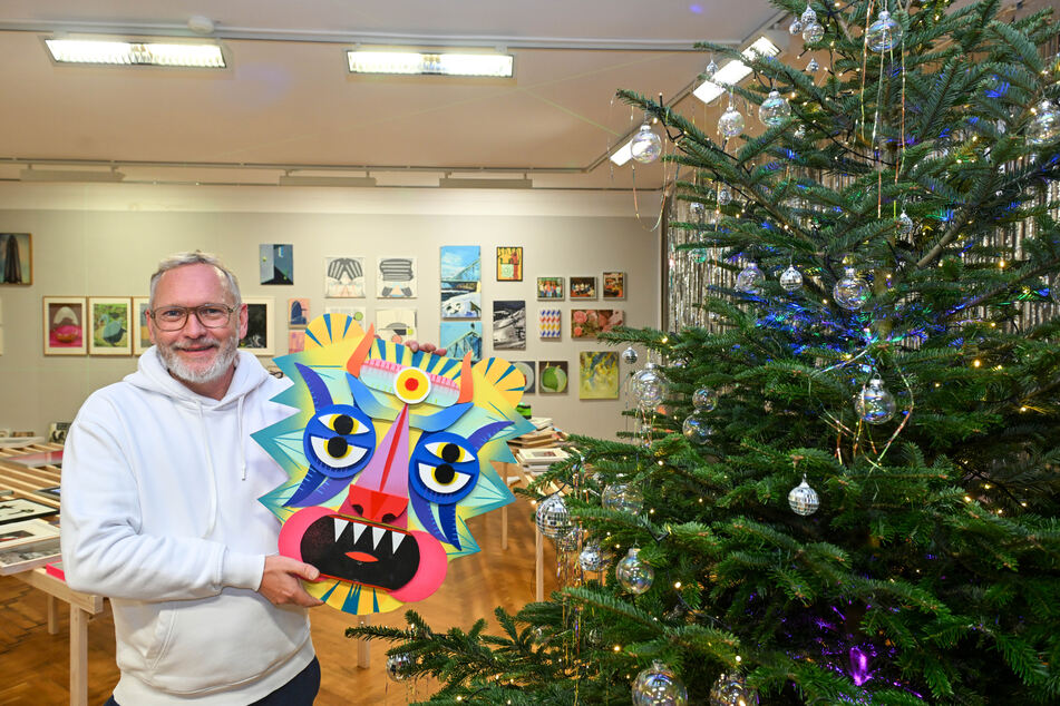 Kunst-Förderer Jens Zander (53) zeigt eine Maske der Künstlerin "Muah", die auf dem Weihnachtsmarkt angeboten wird.