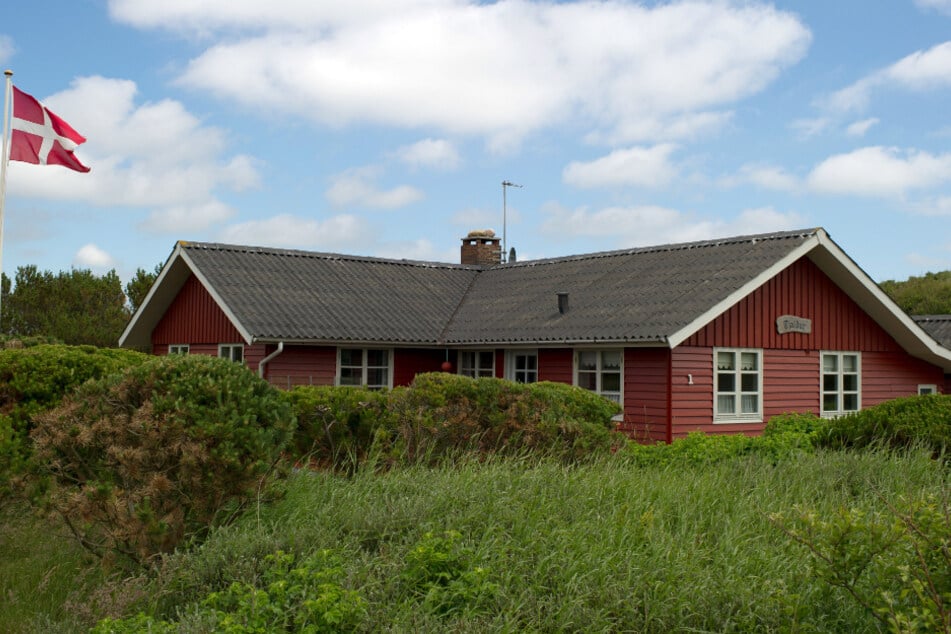 Dänemark, Henne Strand: Ein dänische Fahne weht an einem Ferienhaus in Henne Strand, einem Ferienort an der dänischen Westküste, nördlich von Esbjerg.