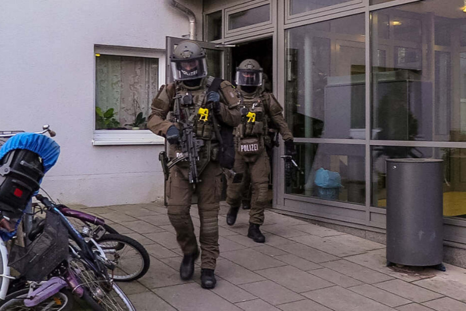 Bewaffnete Einsatzkräfte verlassen nach der Stürmung der Wohnung das Haus.