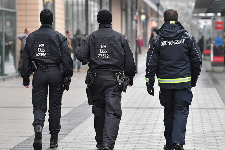 Ein Mitarbeiter des Ordnungsamtes und zwei Beamte der Bereitschaftspolizei auf Streife vor dem Einkaufszentrum Blechen Carré in Cottbus.