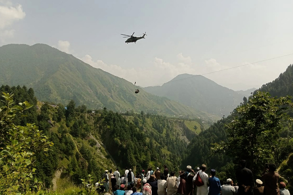Einheimische sehen zu, wie eine Person per Helikopter aus der verunglückten Seilbahn gerettet wird.