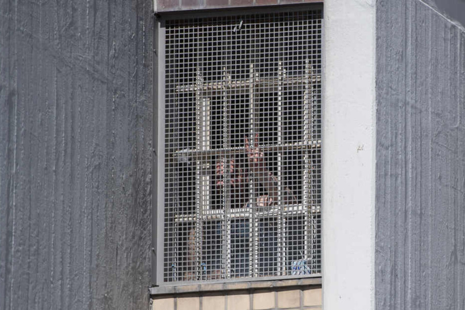 Ein Häftling spreizt in Stuttgart-Stammheim hinter einem vergitterten Zellenfenstern in der Justizvollzugsanstalt (JVA) Stuttgart die Finger. 