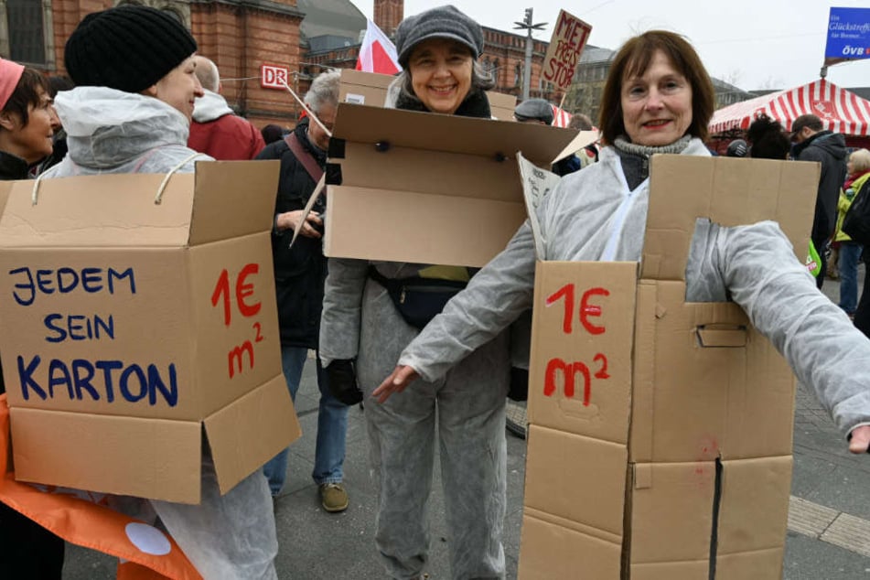 Teilnehmerin der Demonstration "Die Stadt muss allen gehören" in Bremen, haben sich für mehr bezahlbaren Wohnraum Kartons mit Sprüchen übergezogen.