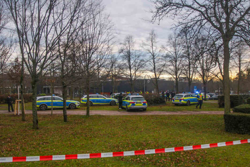 Polizisten stehen hinter einem Absperrband.