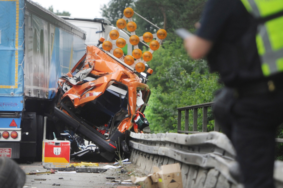 Ein zerstörtes Fahrzeug der Autobahnmeisterei steht neben einem Lastwagen.