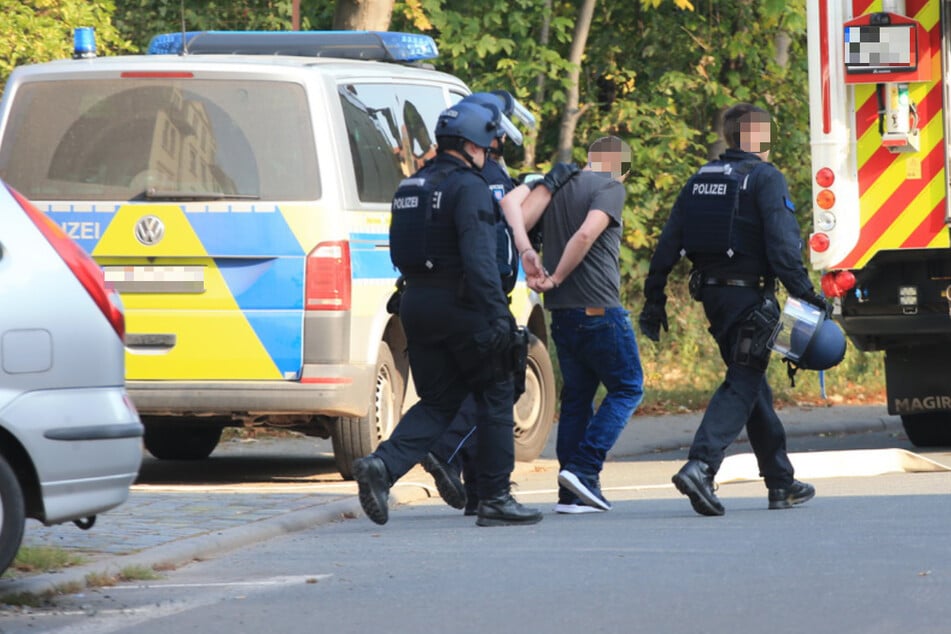Die Polizei führt den Mann in Handschellen ab.