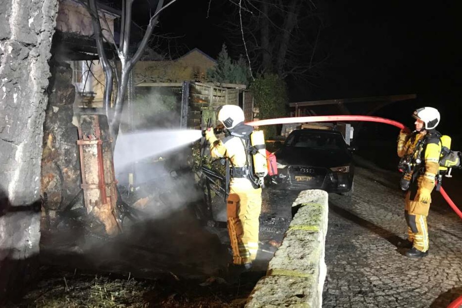 Feuerwehrleute löschen die Flammen am Schuppen.