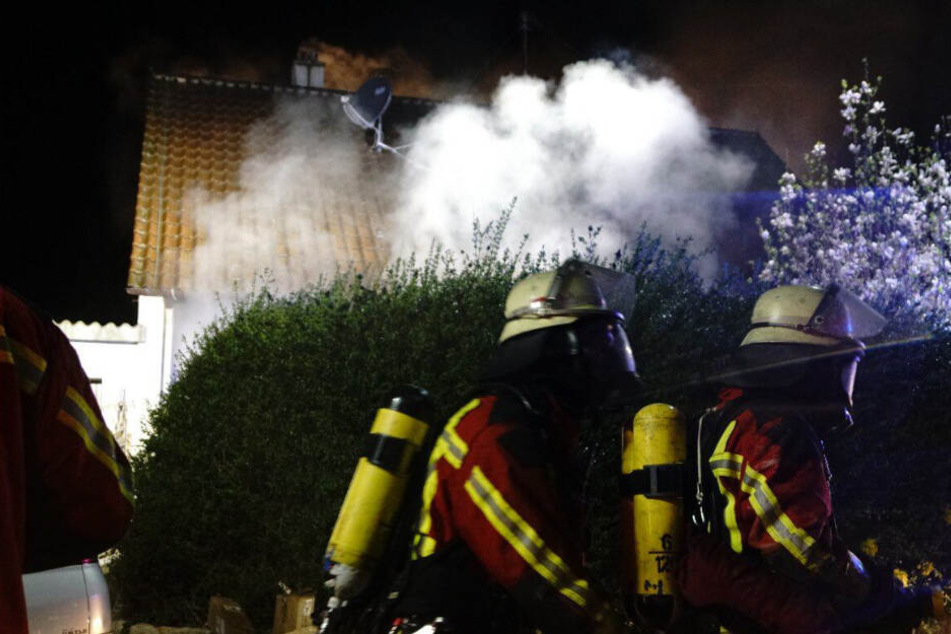 Feuerwehrleute vor dem brennenden Haus.