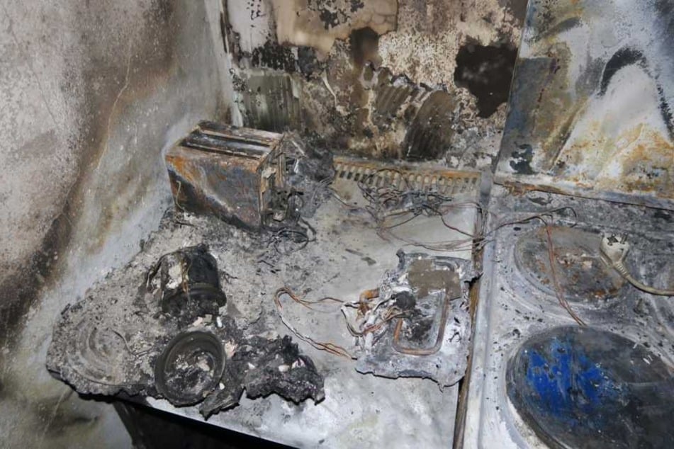 Auf einer Herdplatte liegt der Stecker einer Verteilersteckdose (r.). Sie soll Auslöser des verheerenden Brandes gewesen sein.