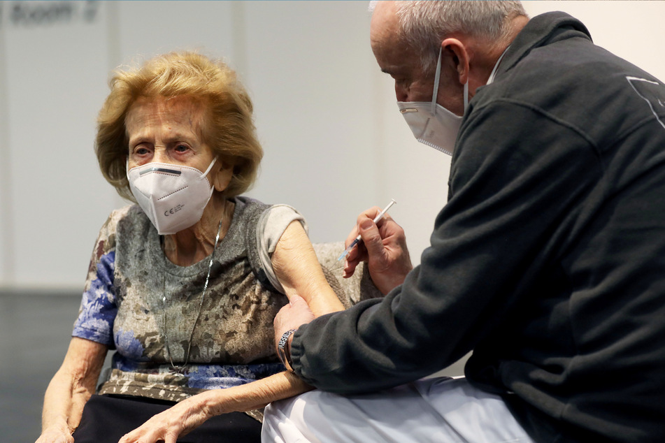 Ein Arzt hält im Impfzentrum die Spritze an den Arm von Elisabeth Steubesand (105). Die älteste Kölnerin hat kein Verständnis für Menschen, die ihre Impftermine absagen, weil ihnen der Impfstoff nicht passt.