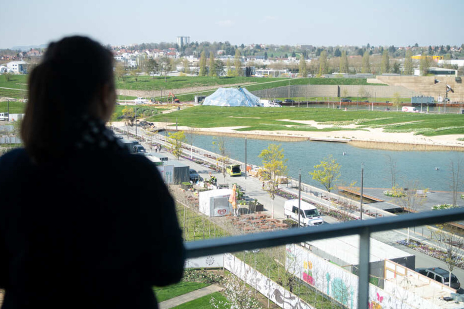 Eine Frau blickt von einem Wohngebäude der Stadtausstellung auf das Gelände der Bundesgartenschau.