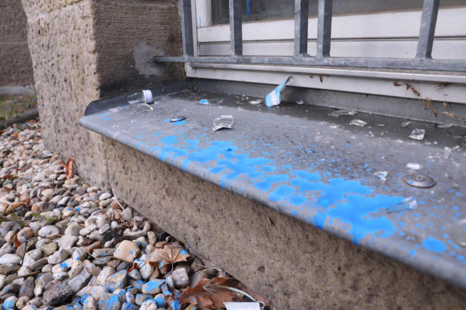Zerschellte Weihnachtsbaumkugeln liegen auf einer blau gefärbten Fensterbank.