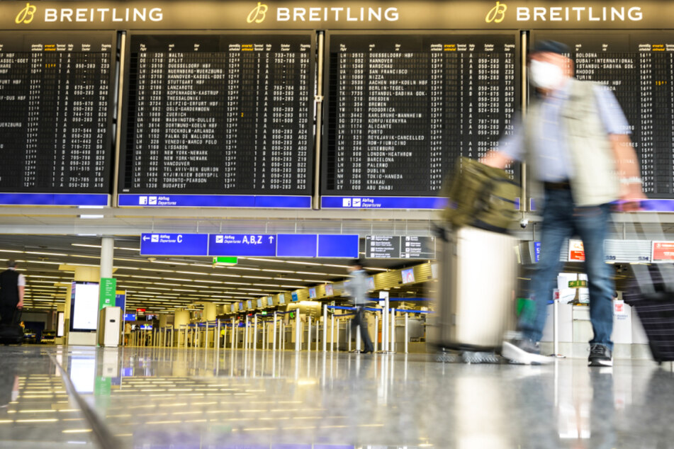 Reisende gehen im Juli mit Gepäck durch die Abflughalle im Terminal 1 am Flughafen Frankfurt.