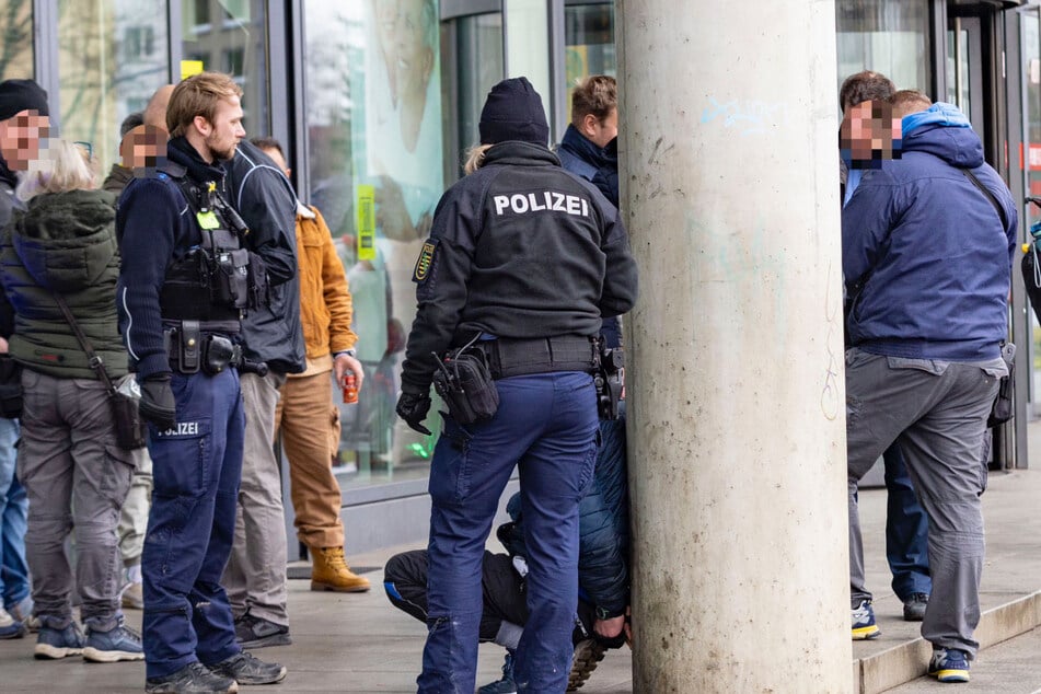 Beamte vor einem vorläufig festgenommenen Mann, der anscheinend aggressiv gegenüber Fahrkartenkontrolleuren wurde.