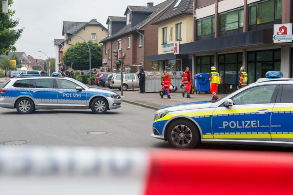 Polizei- und Rettungskräfte stehen vor dem Mehrfamilienhaus in Bargteheide, in dem die Frau erschossen wurde.