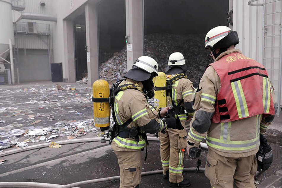 Die Feuerwehrmänner rücken mit Schutzkleidung und Atemgeräten in die Lagerhalle vor.