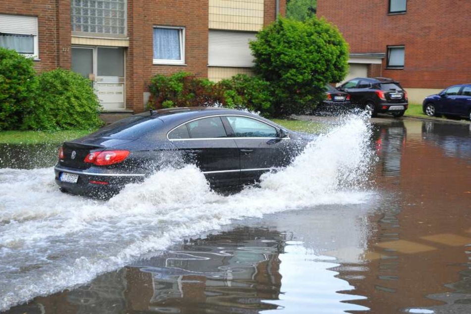 Ein Auto fährt durch eine überflutete Straße in Mönchengladbach.