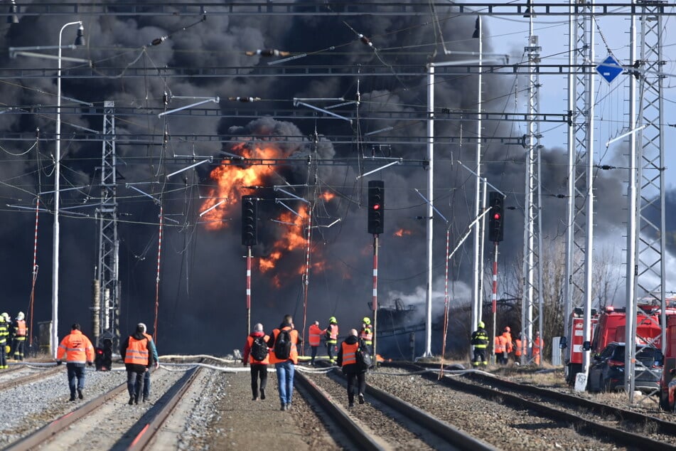 Feuerwehrleute sind vor einem defekten Eisenbahntankwagen im Einsatz, aus dem Benzol, eine brennbare und giftige Flüssigkeit, ausläuft.