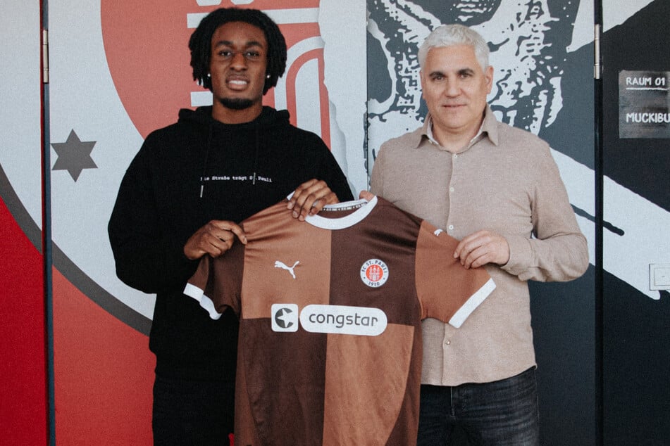 Romeo Aigbekaen (20, l.) und St.-Pauli-Sportchef Andreas Bornemann (53) posieren mit dem Trikot der Kiezkicker.