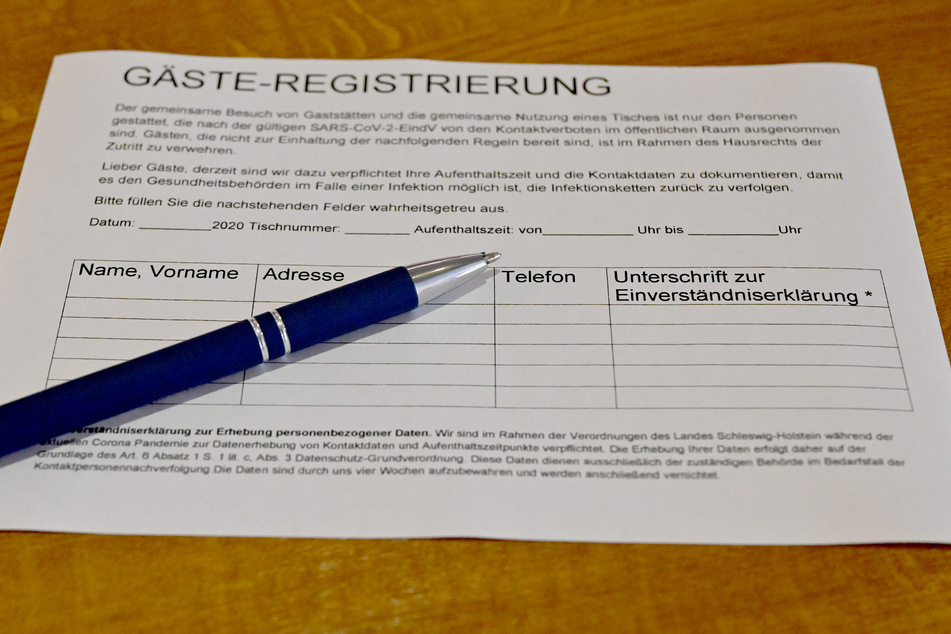 Ein Zettel für die Gäste-Regstrierung liegt in einem Restaurant auf einem Tisch.