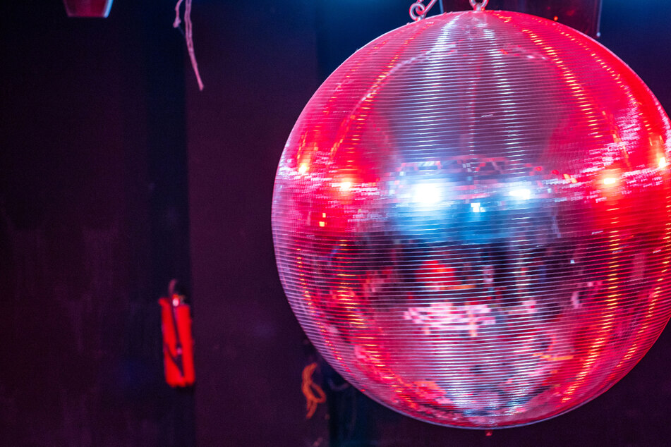 Die farbig beleuchtete Discokugel dreht sich über der Tanzfläche in einer Diskothek - viele Club-Betreiber in Hessen sehen die neuen Corona-Regeln in dem Bundesland skeptisch.