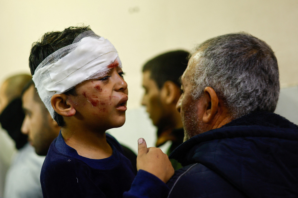 A wounded boy reacts as people mourn next to bodies of Palestinians killed in Israel strikes, at Nasser hospital in Khan Younis in the southern Gaza Strip on December 1, 2023.