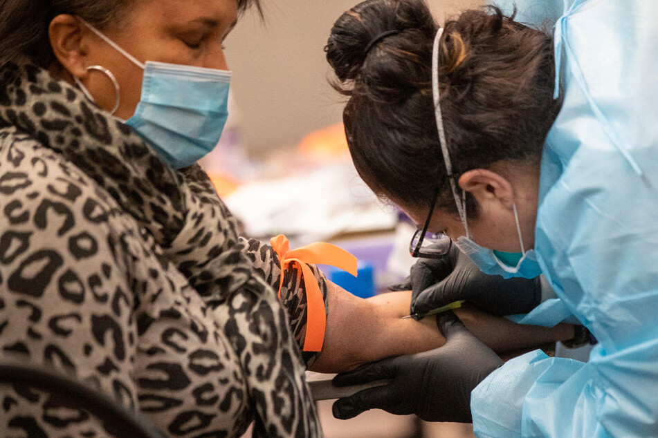 Eine Krankenpflegerin führt für einen Antikörpertest eine Blutabnahme bei einer Frau in einer Test-Station in der Abyssinian Baptistenkirche in Harlem in New York durch.