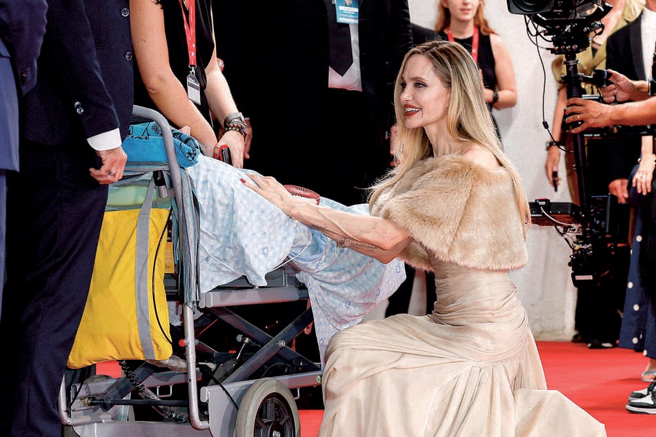 With a smile on her face, actor Angelina Jolie knelt down in front of her fan to greet him.