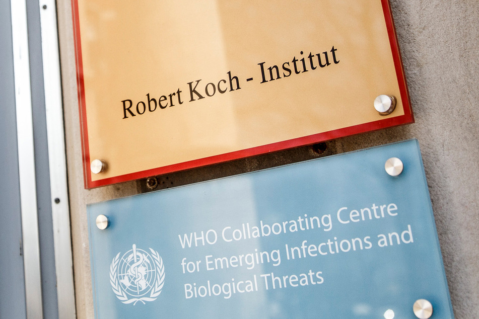 Ein Schild mit der Aufschrift "Robert Koch-Institut" weist auf den Eingang des Gebäudes hin.