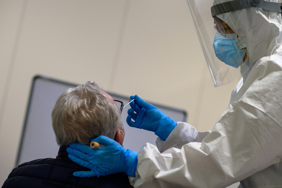 Sachsen-Anhalt, Magdeburg: Ein Mitarbeiter des Universitätsklinikums Magdeburg führt bei einem Mann einen Antigentest auf das Coronavirus durch.